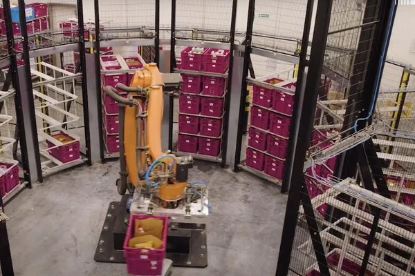 Ramię robota przekładające pojemnik trapezowy Utz na właściwą p&oacute;łkę